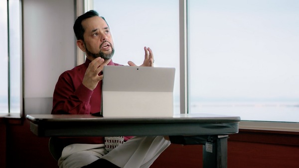 Man at desk speaking while looking at tablet screen