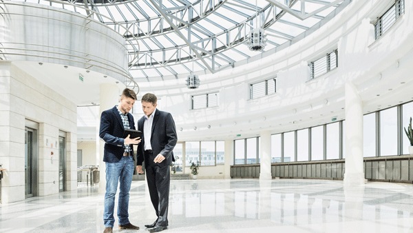 Two men talking while looking at a tablet 