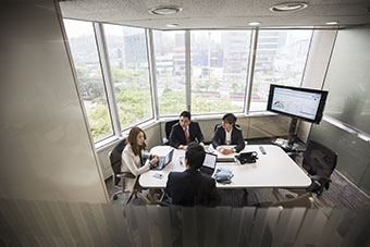 Meeting Server 的參與者坐在桌前並透過螢幕共同作業。
