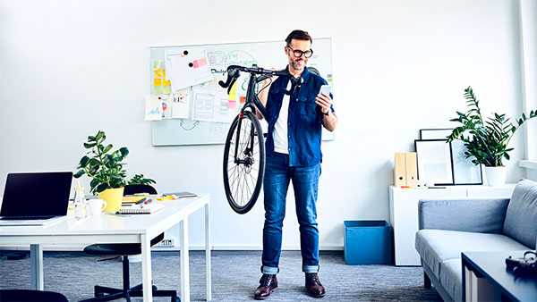 一位男子在小型企業辦公室內扛著一台自行車