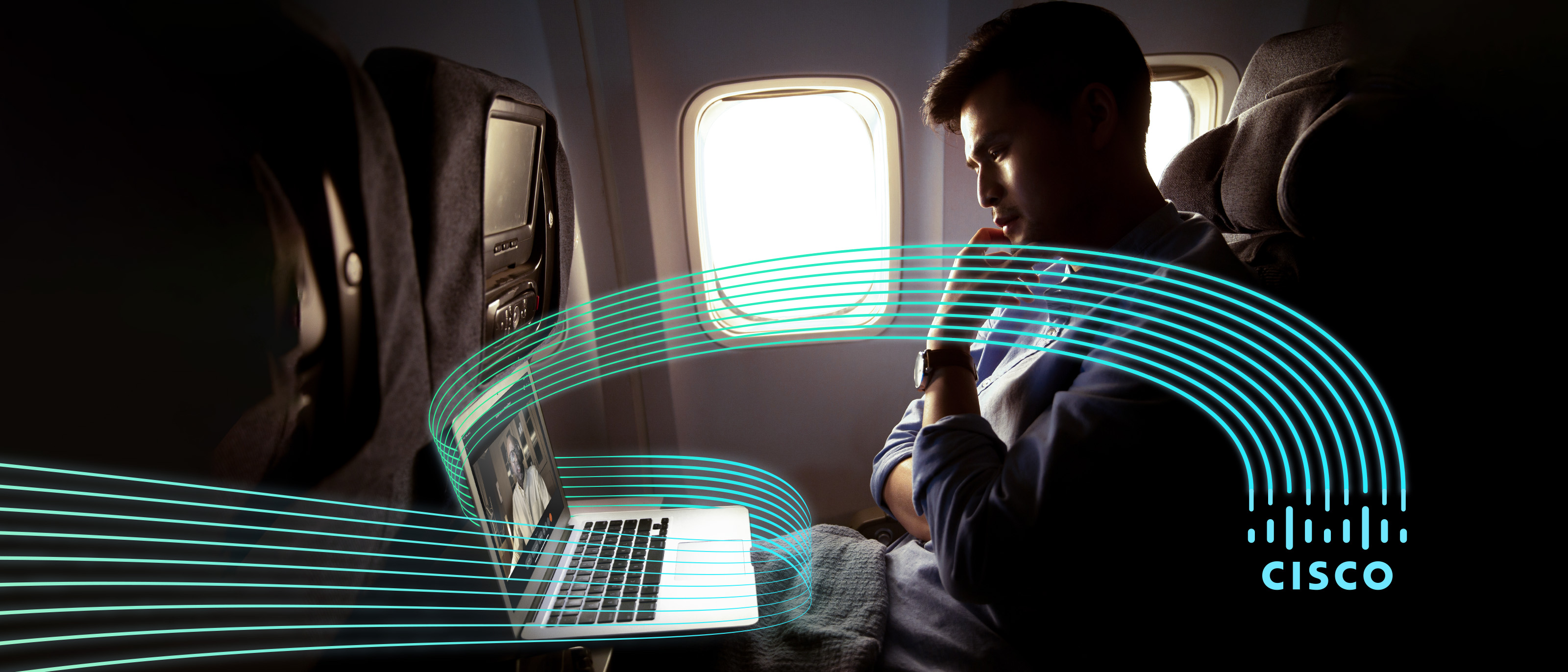 From an aeroplane seat man views laptop screen wrapped in Cisco logo