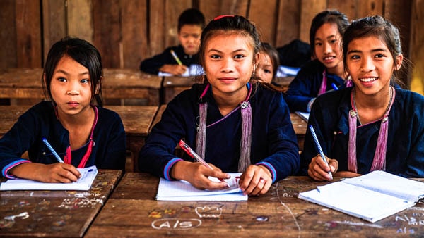 Three young girls smiling in a classroom