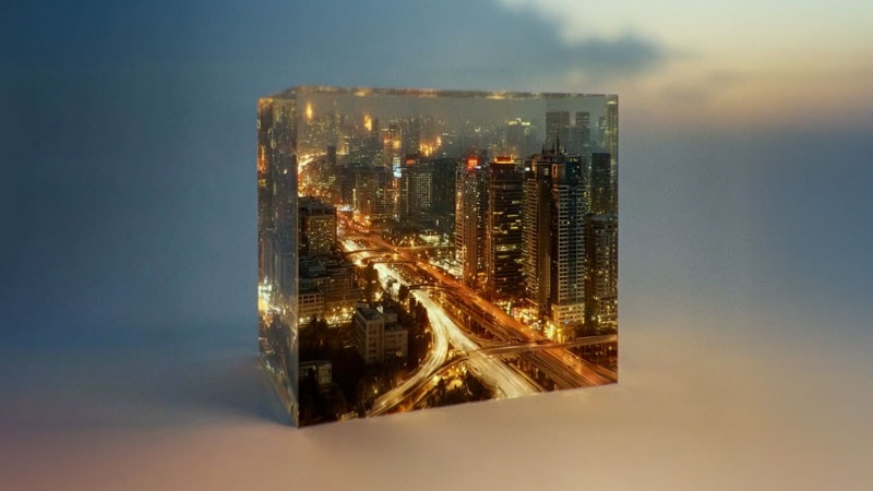 Transparent cube containing a miniature night city with glowing skyscrapers and highways.