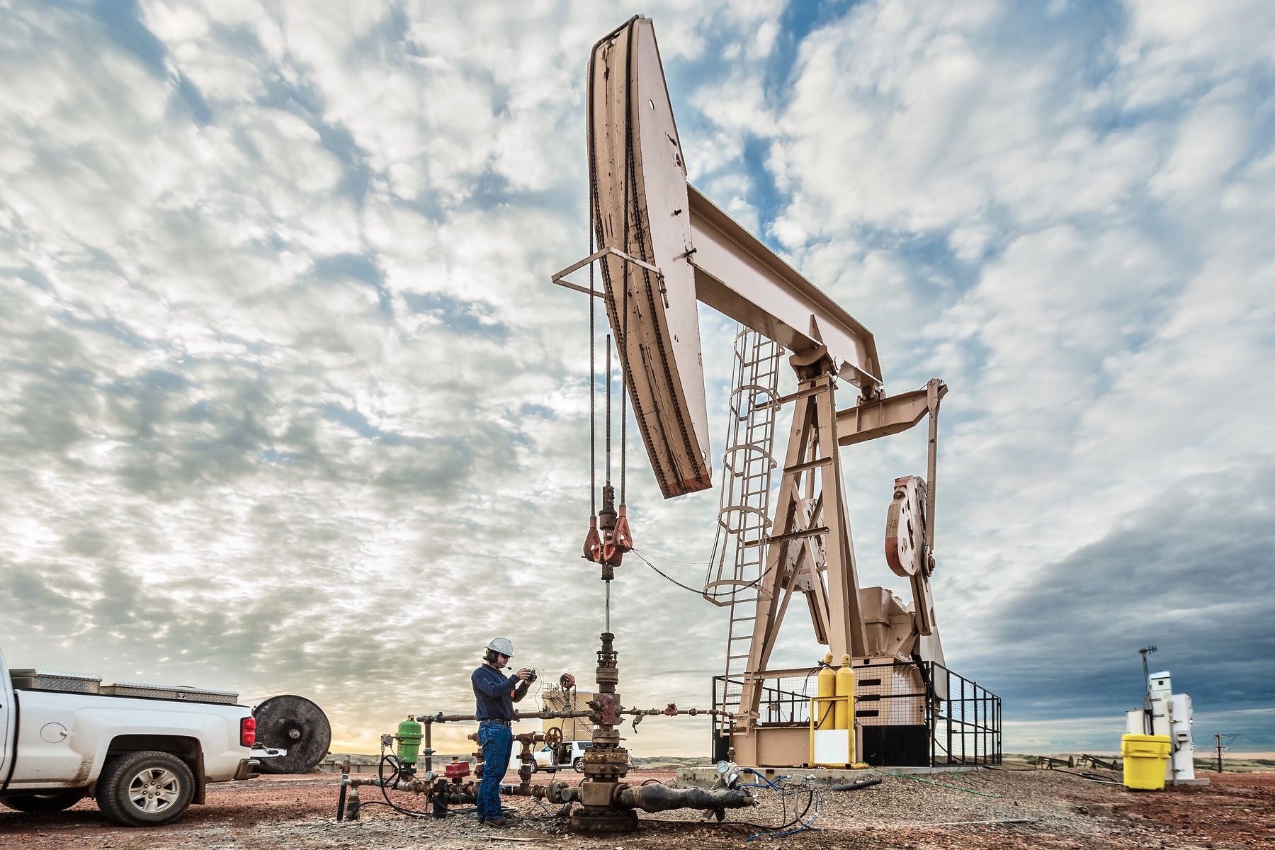 Worker on device in front of oil drill