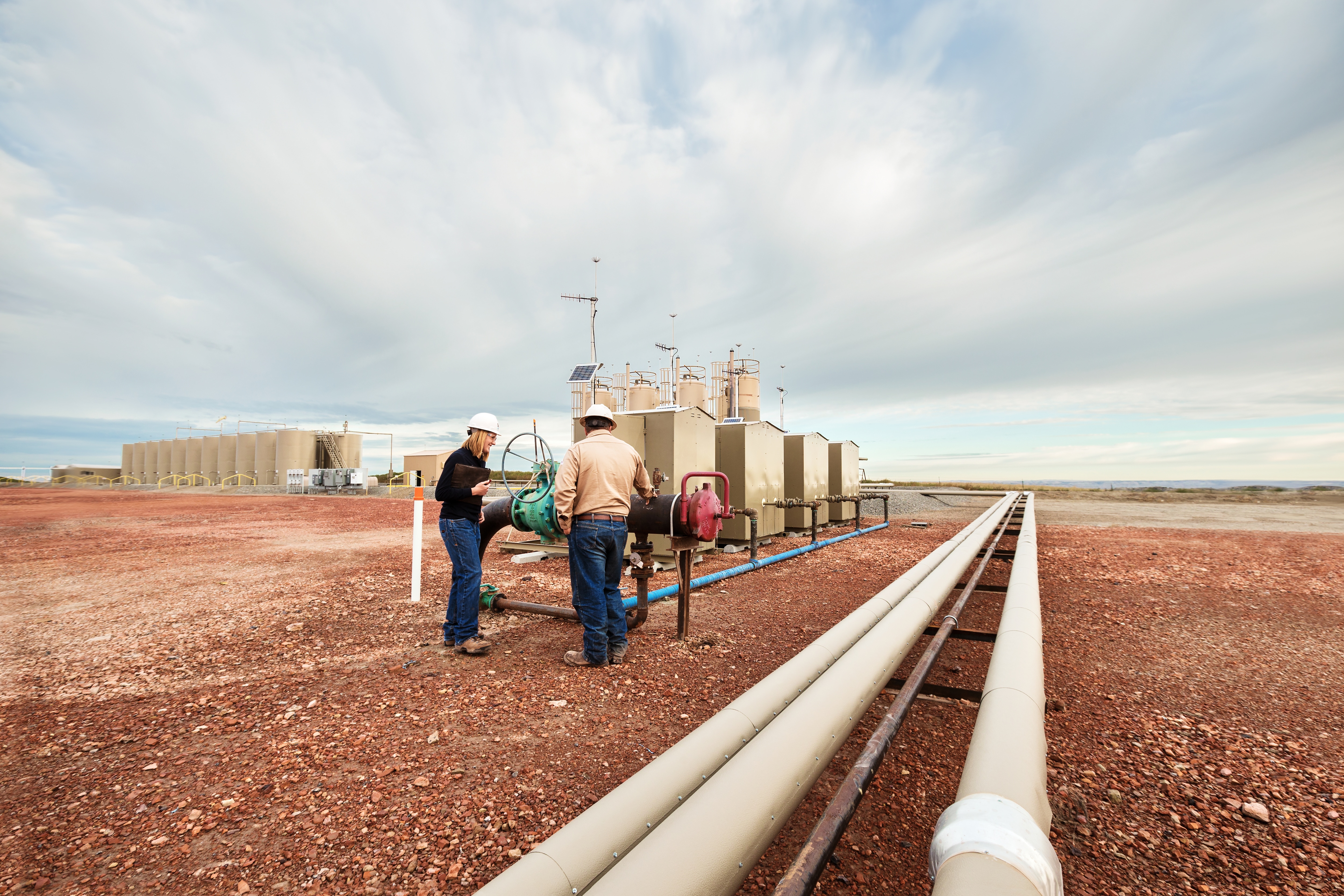 Workers talk on oil field.