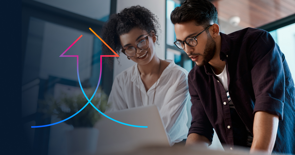 ​​Two business professionals standing at a desk with a laptop.​