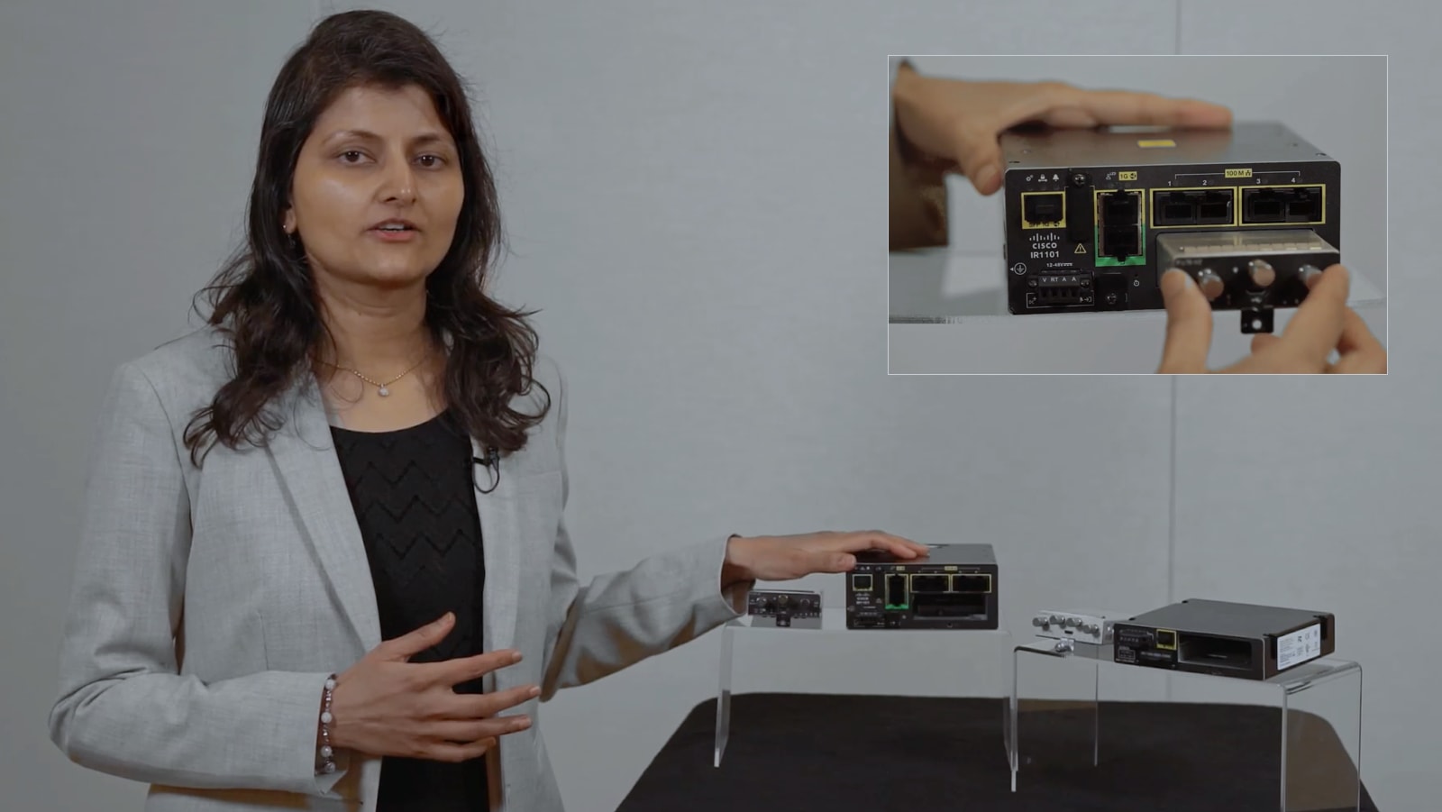 Woman holding the Catalyst IR1100 Rugged Series Router with pluggable modules and expansion modules on either side.