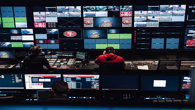 Broadcast production crew operating a stadium control room.