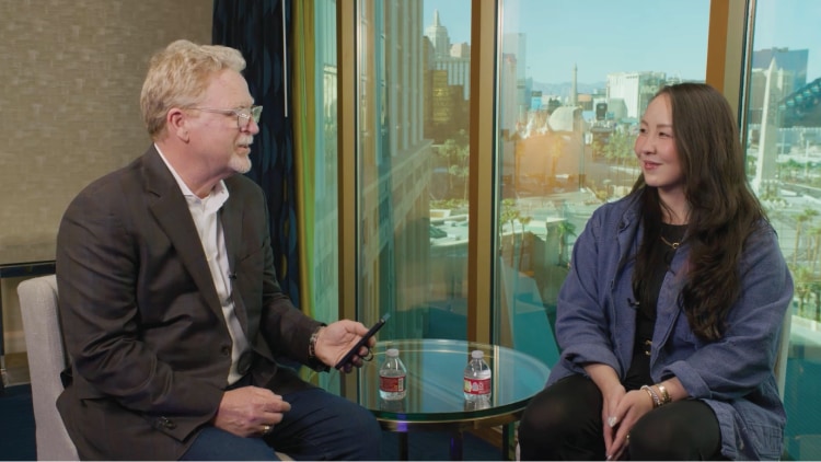 Amy Chang speaks with an interviewer in front of a city skyline.