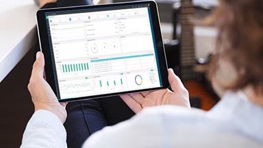 Person holding a tablet displaying a data analytics dashboard with various charts and graphs.