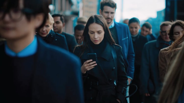 Woman looking at cell phone on a crowded sidewalk