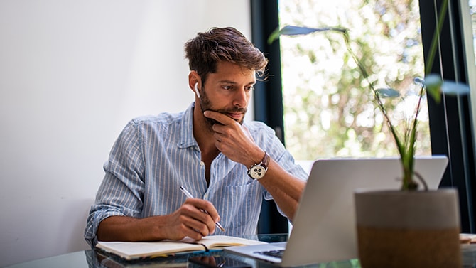 Persona che guarda lo schermo del laptop e tiene in mano una penna