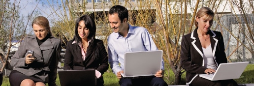 Four business people working outside on laptops